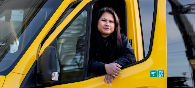 En kvinnlig förare som kör servicebil. 